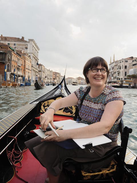 Watercolor artist Liz Steel sketches from a boat in a city waterway.