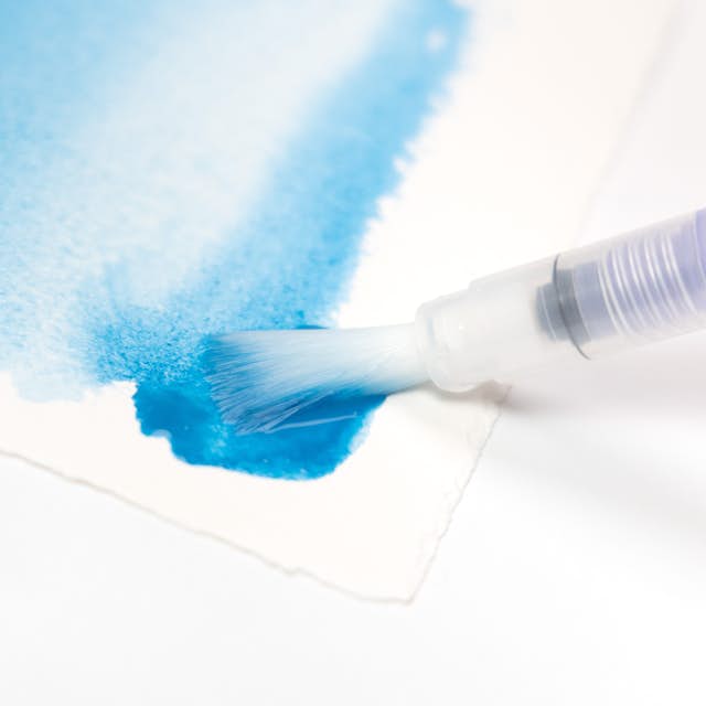 The Niji Flat Waterbrush shown laying down a blue watercolor wash.